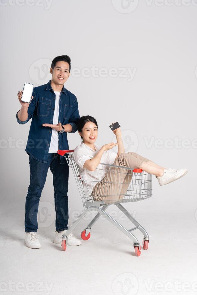 Happy smiling couple pushing supermarket cart isolated on white background photo