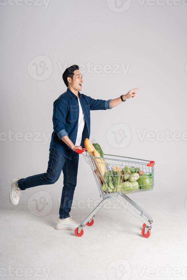 Happy smiling man pushing supermarket cart isolated on white background photo
