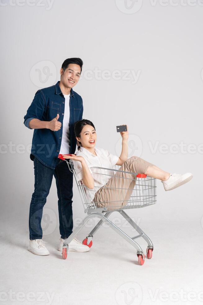 Happy smiling couple pushing supermarket cart isolated on white background photo