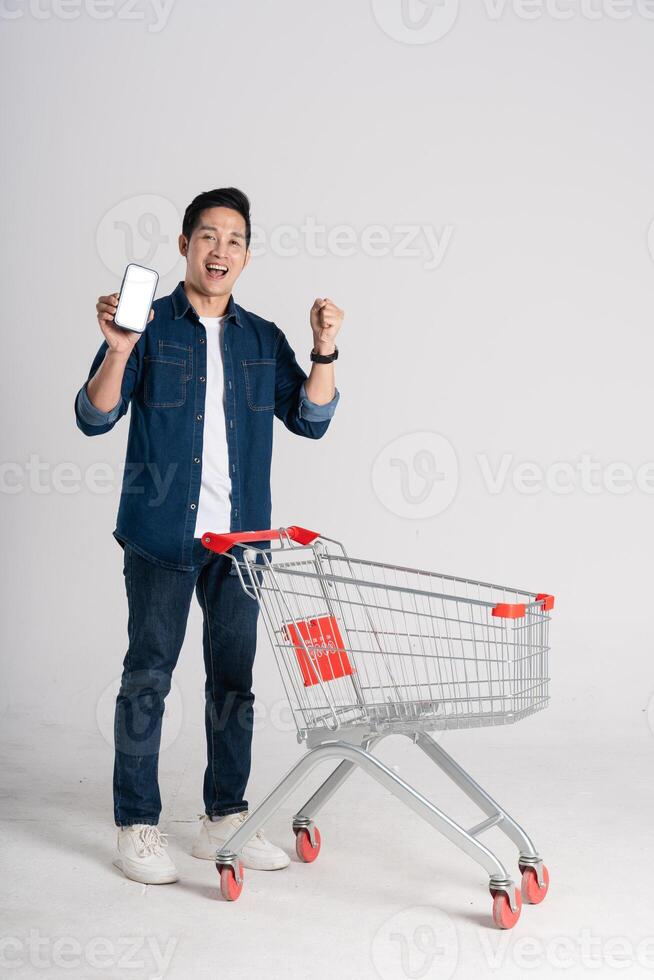 Happy smiling man pushing supermarket cart isolated on white background photo