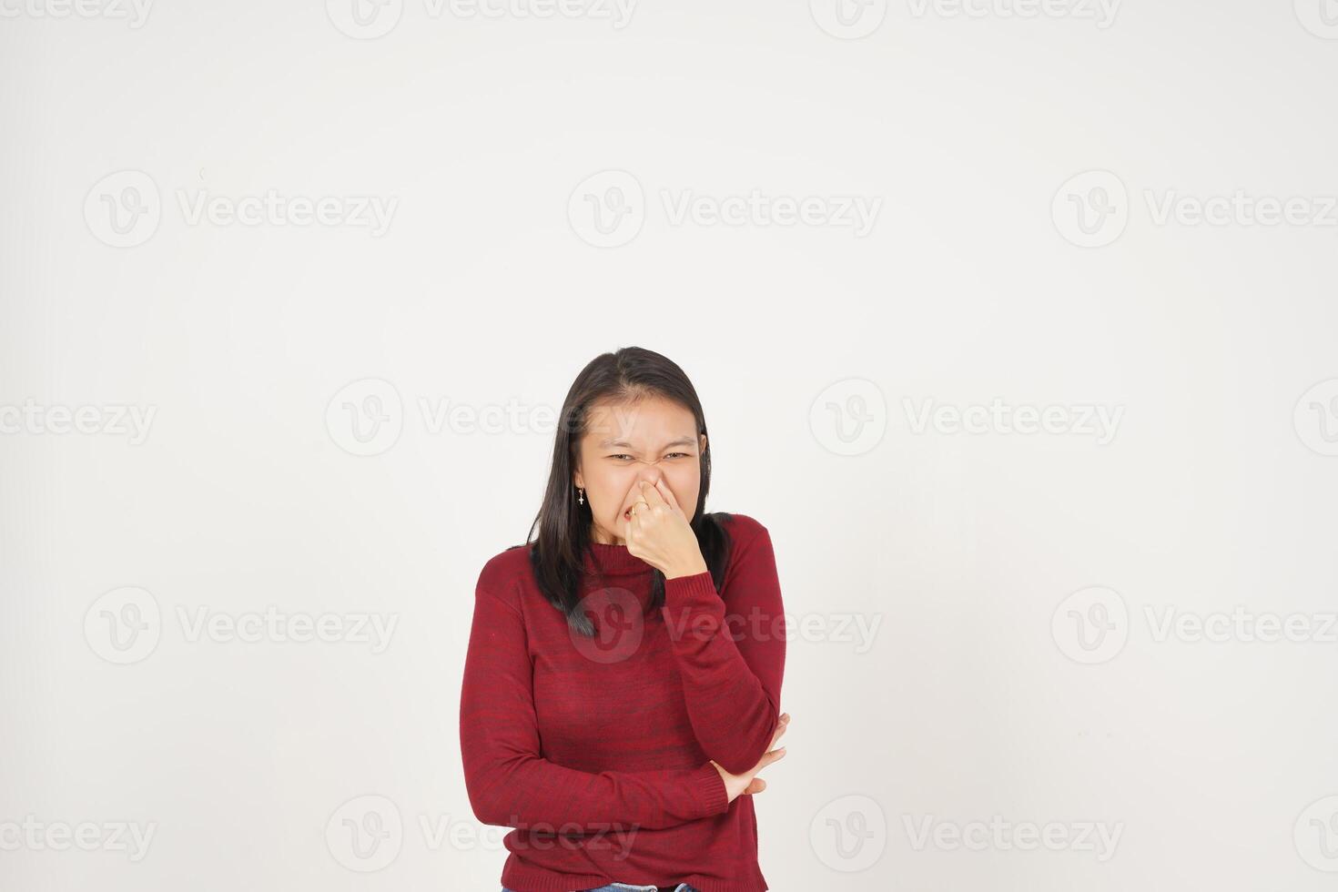 joven asiático mujer en rojo camiseta oliendo alguna cosa apestoso y asqueroso aislado en blanco antecedentes foto