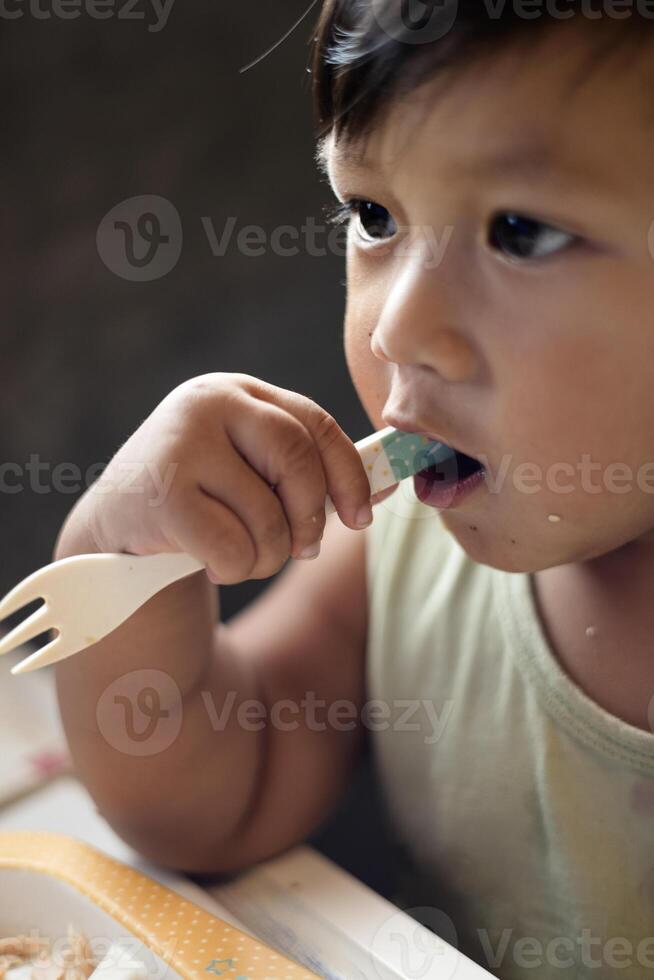Little boy holds a fork in his mouth. photo