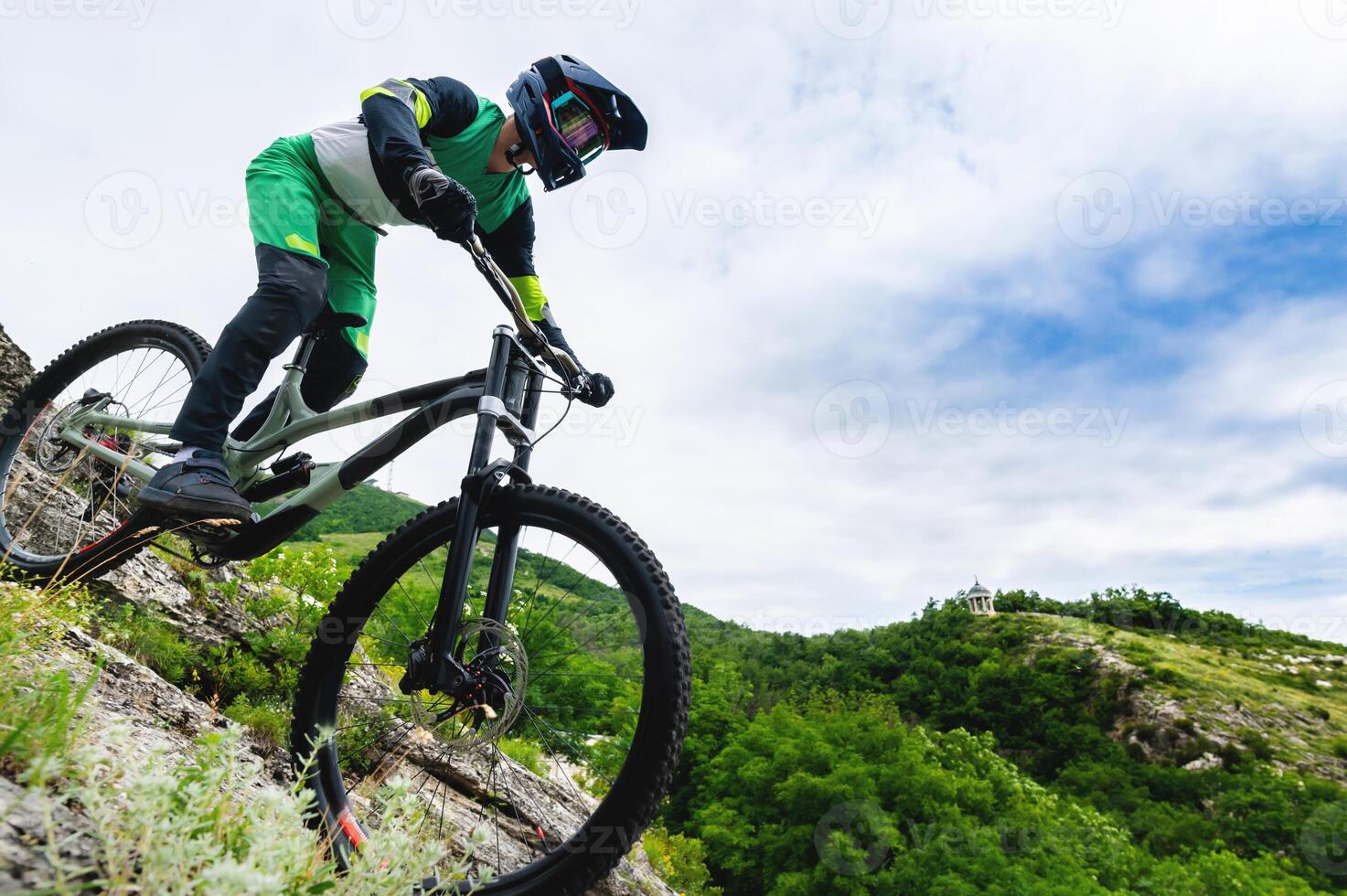 Professional cycling. Downhill descent from the mountains by bicycle. Young rider going down the mountain on a mountain bike in summer surrounded by greenery photo