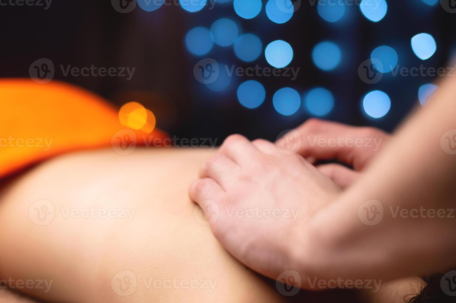 Close-up of a woman's neck and trapezium being massaged by a male masseur in shallow depth of field photo