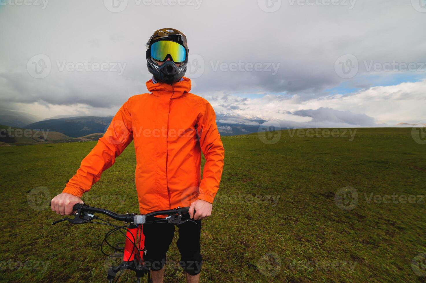 Portrait of a racer in full protection of a full face mask on a bicycle or motorcycle in the summer mountains. The concept of attracting youth to outdoor sports photo