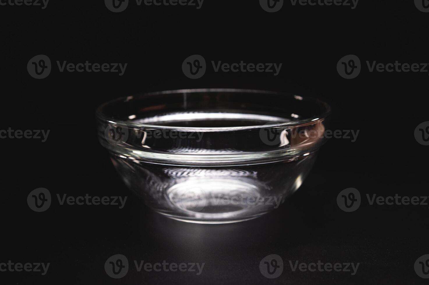 Empty glass plate or salad bowl for one person, on a black background, close-up photo