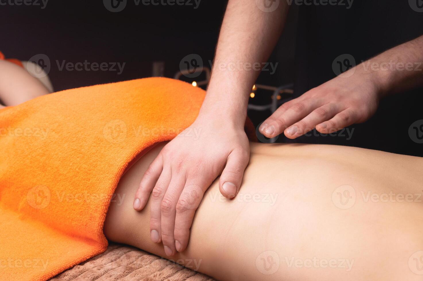 Side view in shallow depth of field. Massage of the lower back by a male masseur. Volumetric light. Live photography photo