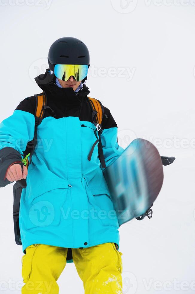 de cerca de un masculino snowboarder zancadas abajo el Pendiente vistiendo un casco y máscara con su tabla de snowboard foto