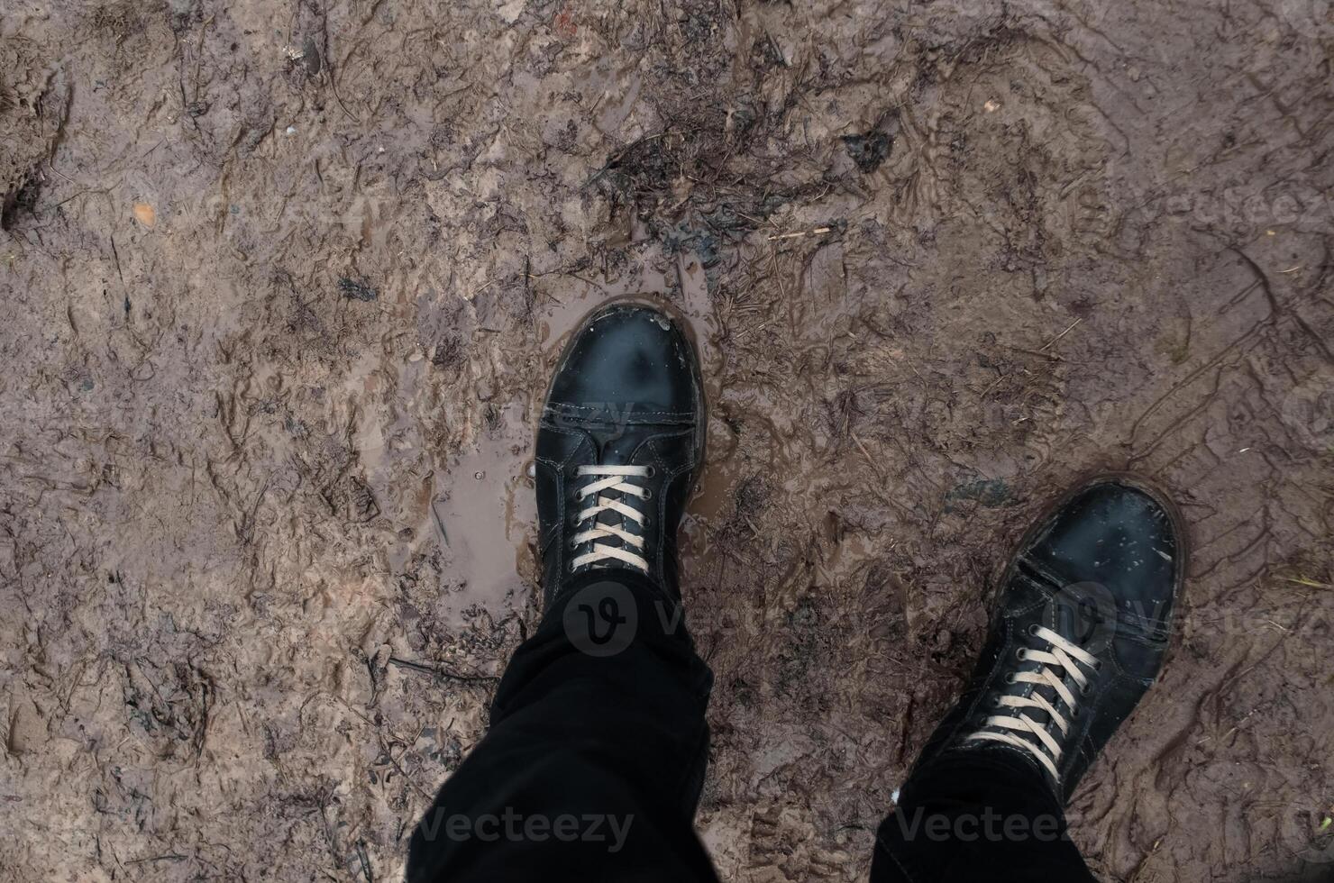 Boots standing in mud and slush, pov. Concept bad weather, off-road, thaw photo