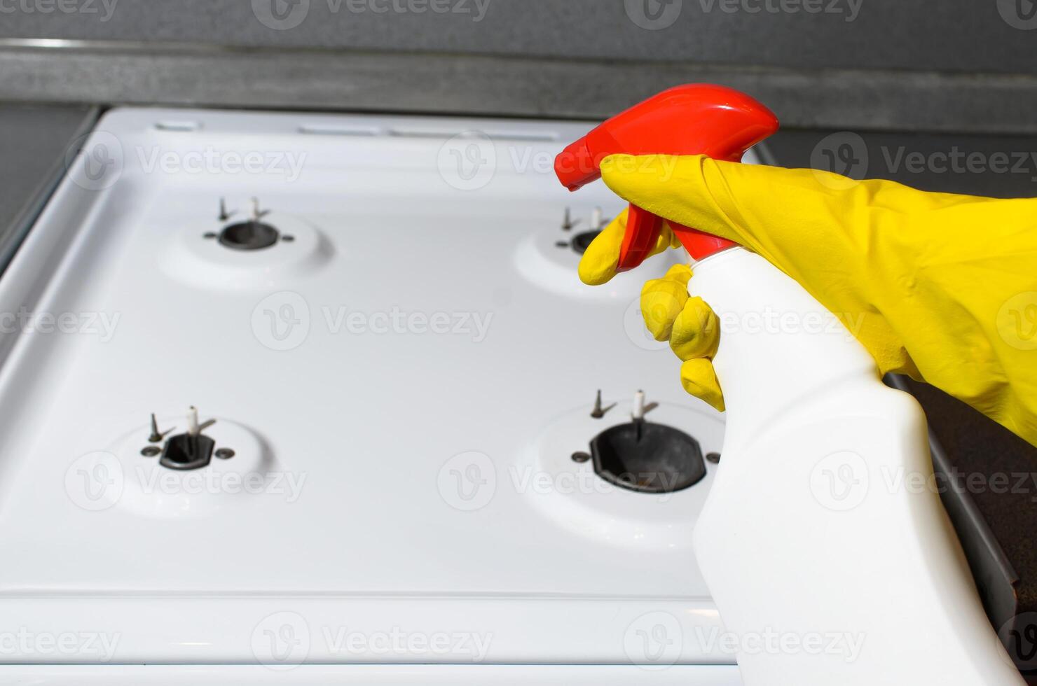 Female hand in glove splashing with a chemical spray. Woman cleaning kitchen apartment with cleaning spray. Hygienic house cleaning photo