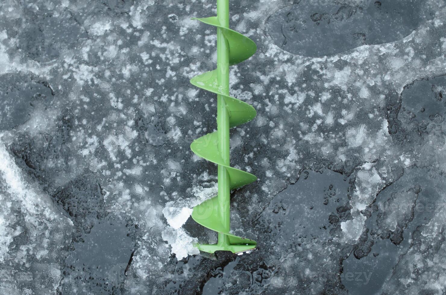 Drill lying on ice, top view. Equipment for winter fishing, drilling holes photo