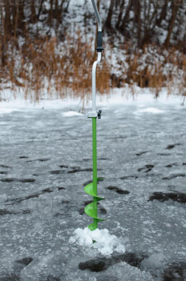 Drill standing in ice. Equipment for winter fishing. photo