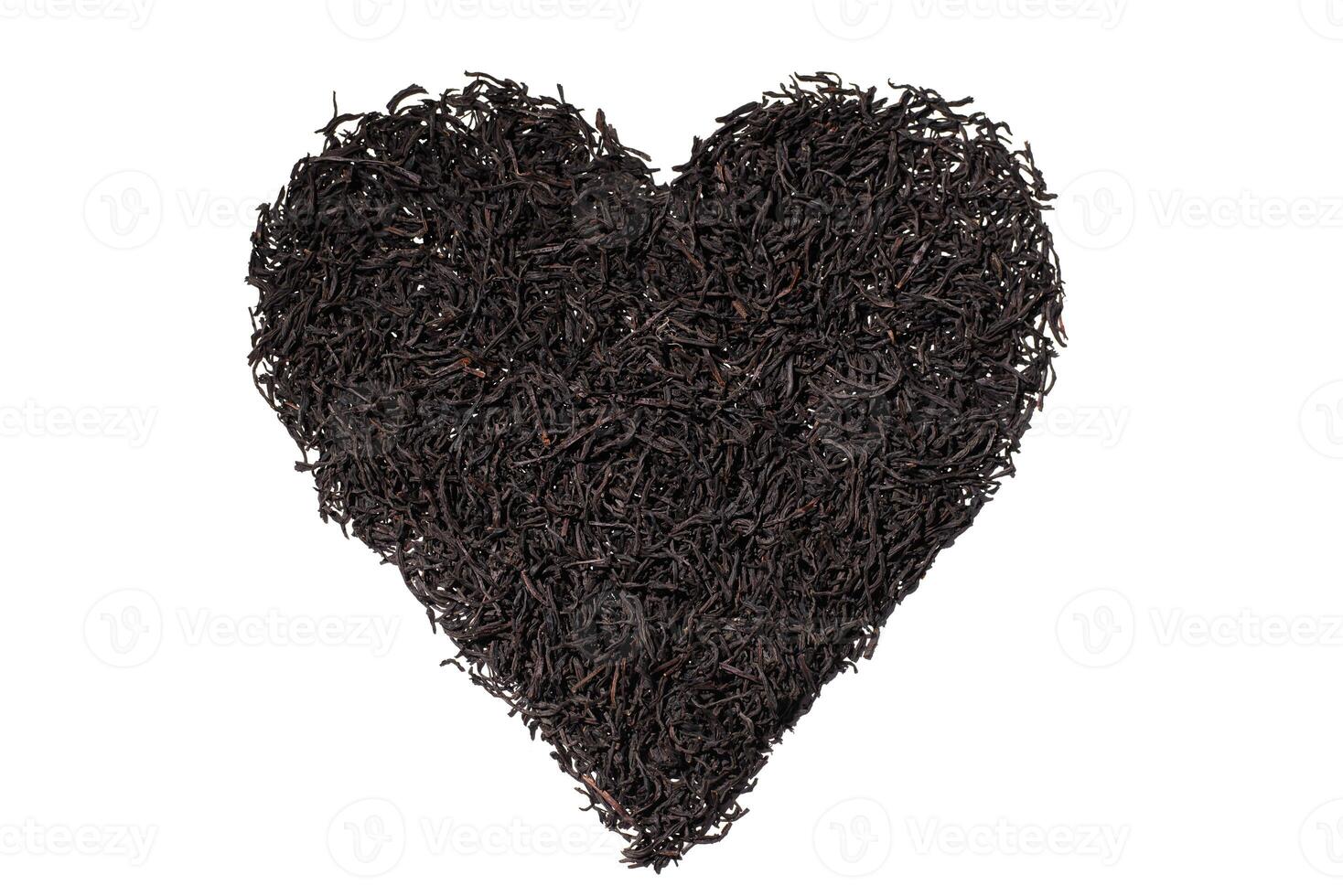 Dry black tea leaves in the shape of a heart. Pile of tea isolated on white background, top view. Creative concept of love for tea. photo