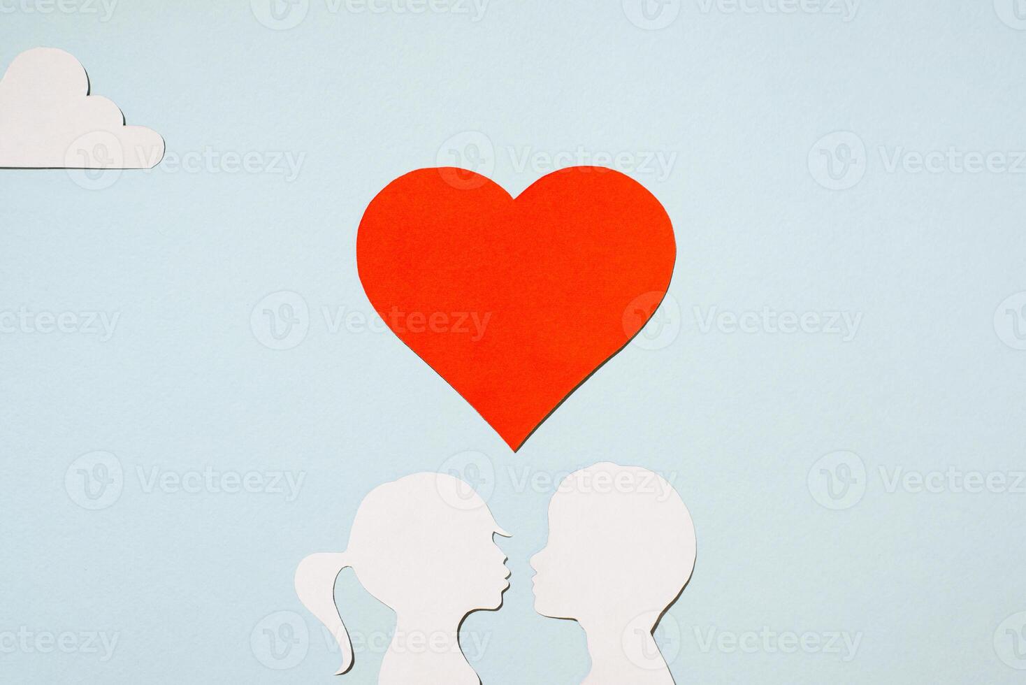 Valentine's Day concept. Kissing girl and boy silhouettes. Creative love card. Red heart and clouds on a pastel blue background. Flat lay, top view. photo