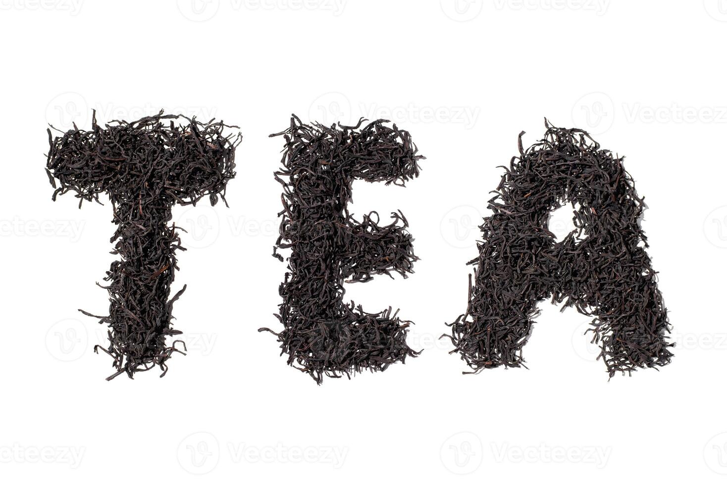 Word Tea made from dry tea leaves. Ceylon tea leaves isolated on white background, top view. photo