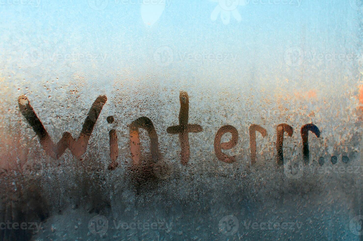 invierno congelado ventana. creativo ortografía de el palabra invierno, medio frío y congelación. escarchado modelo en vaso, soleado Mañana. foto