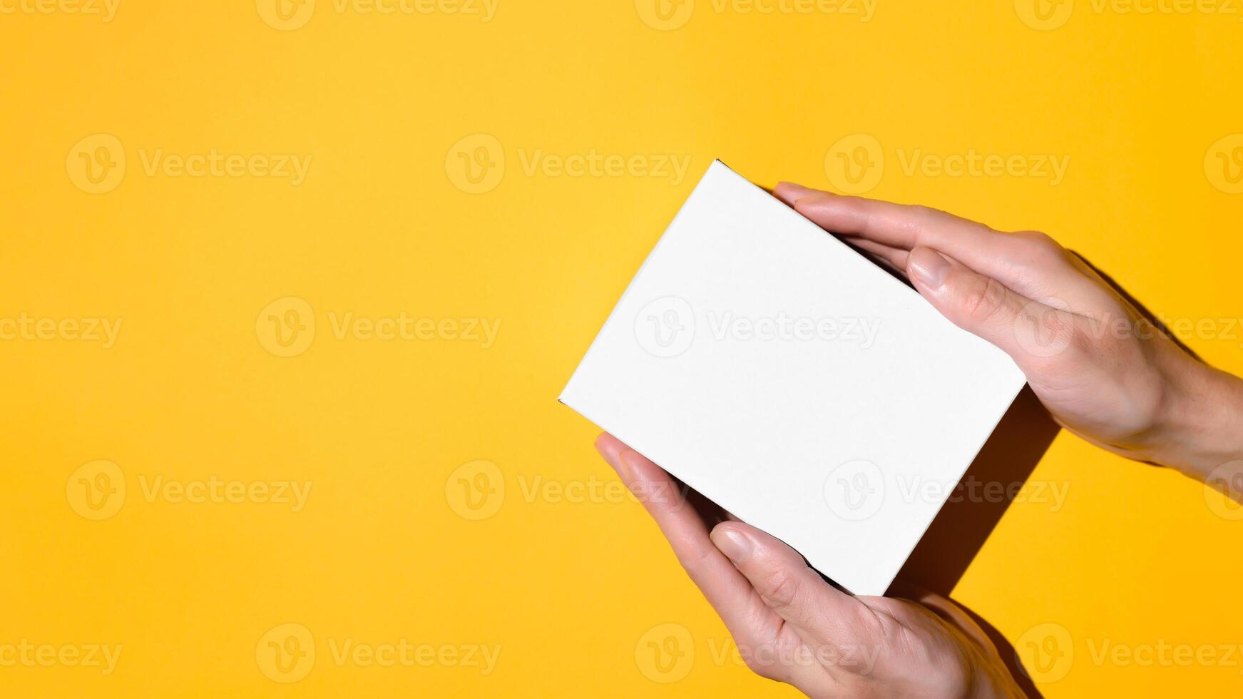 Male hands holding a box on a yellow background, flat lay. Empty white box mock up. Top view, copy space. Delivery concept, gift box. photo