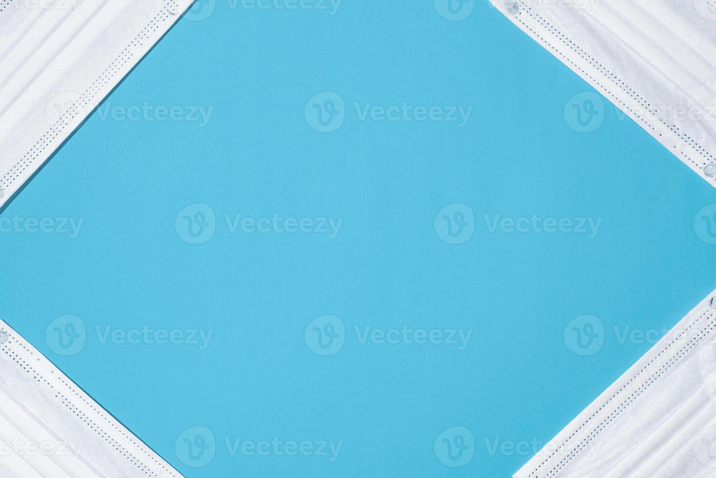 Medical face masks on a blue background, rhombus-shaped frame. Copy space, flat lay photo