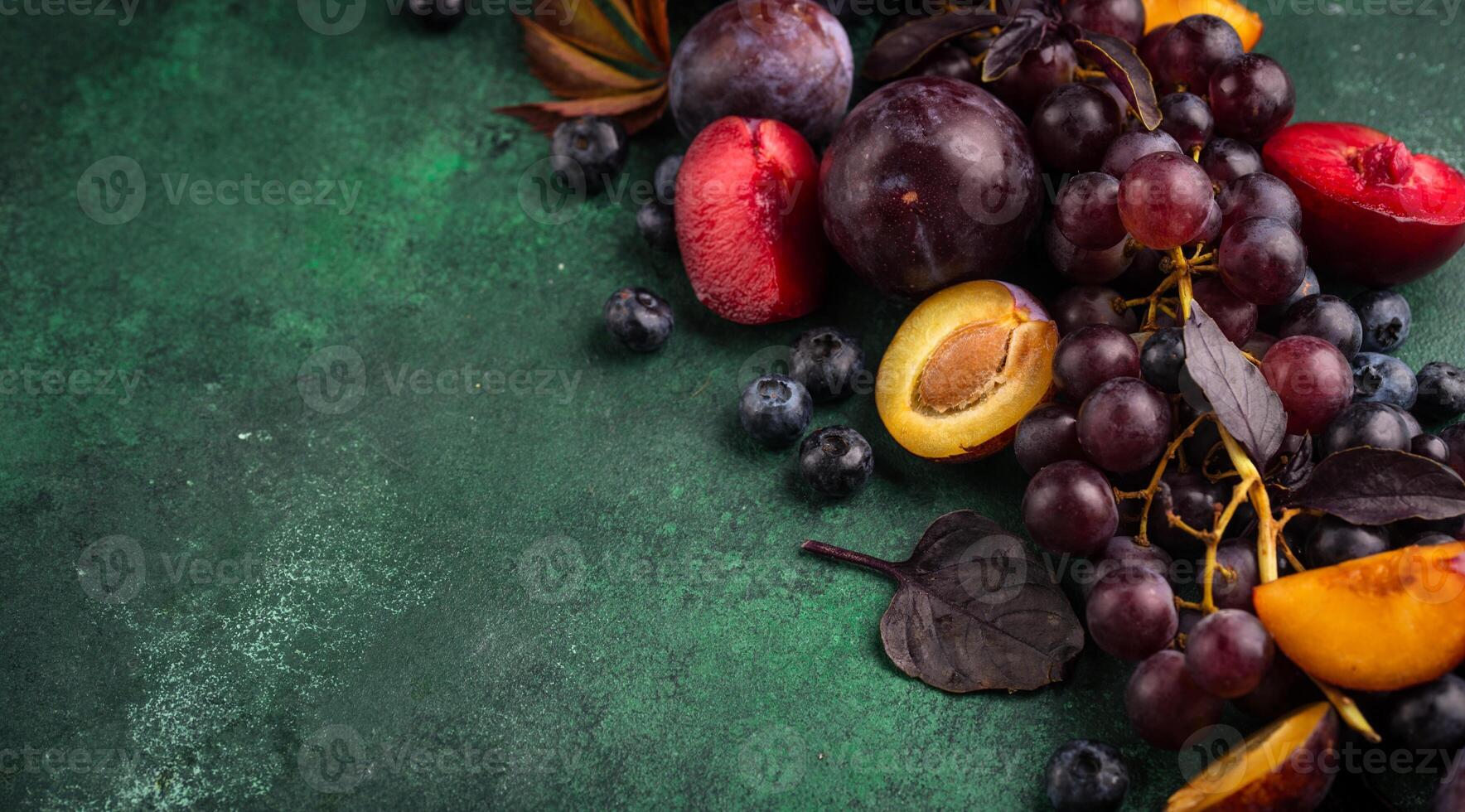 Assortment of purple fruit plum, grape, blueberry and basil photo