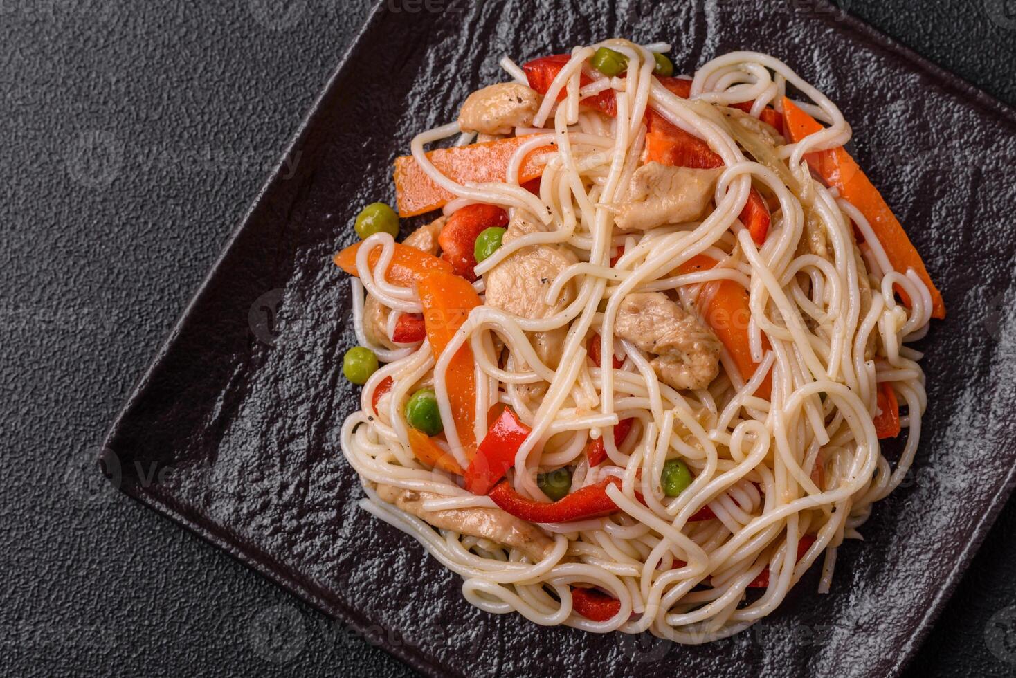 Delicious rice noodles or udon with chicken, carrots, pepper, salt, spices and herbs photo