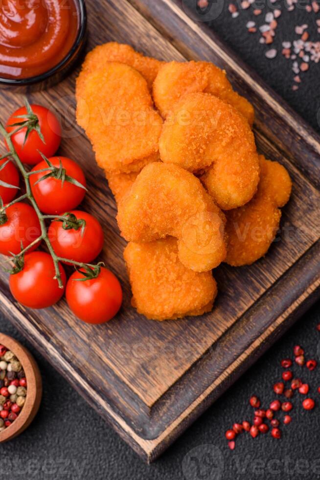 Delicious fresh crispy chicken nuggets on a dark concrete background photo