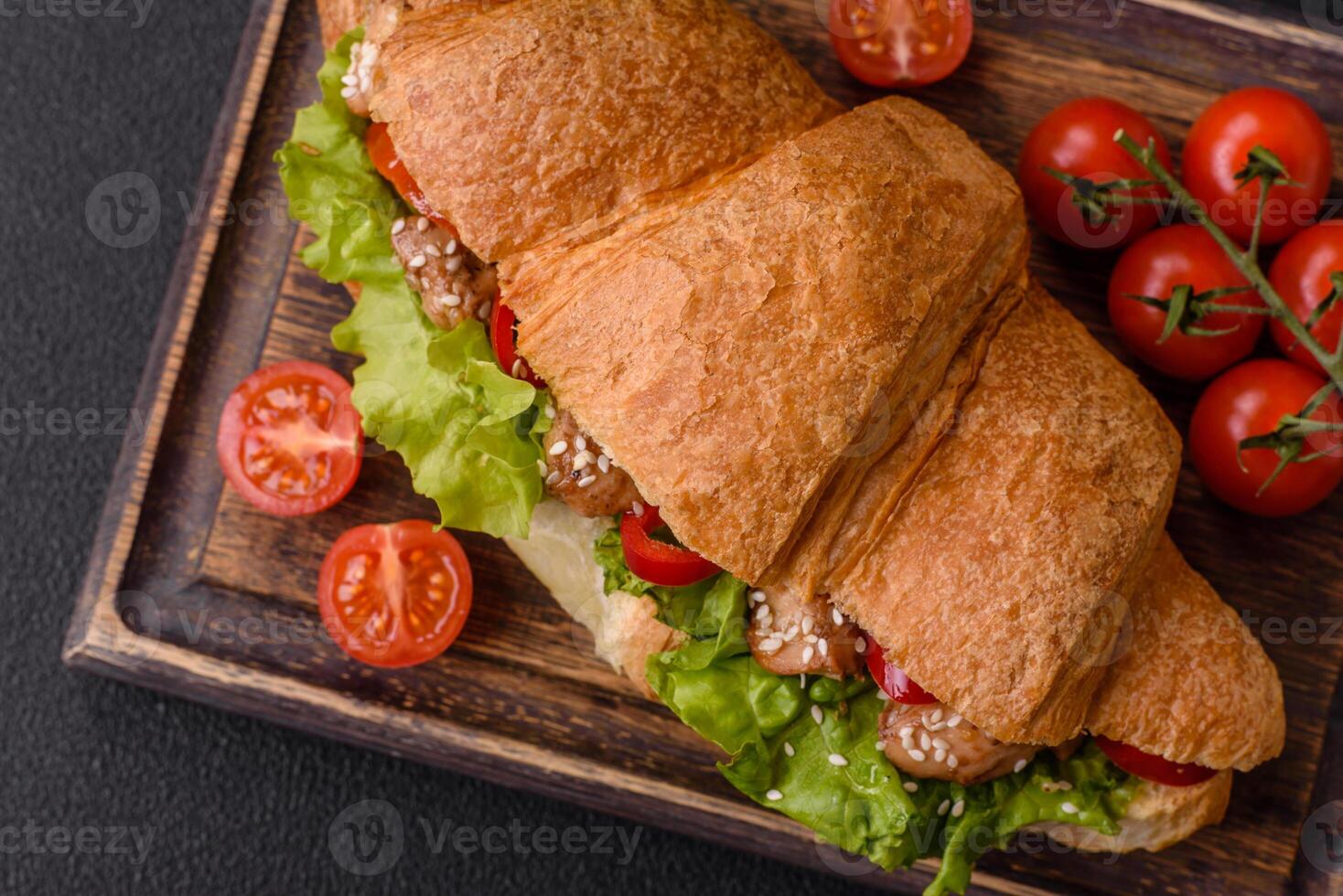 Delicious fresh crispy croissant with chicken or beef meat, lettuce, tomatoes, spices and sauce photo