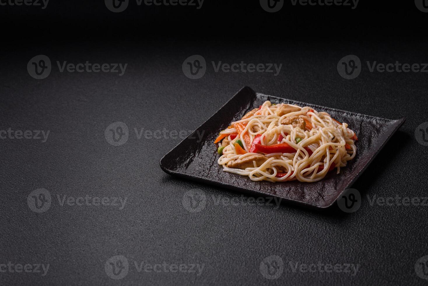 Delicious rice noodles or udon with chicken, carrots, pepper, salt, spices and herbs photo