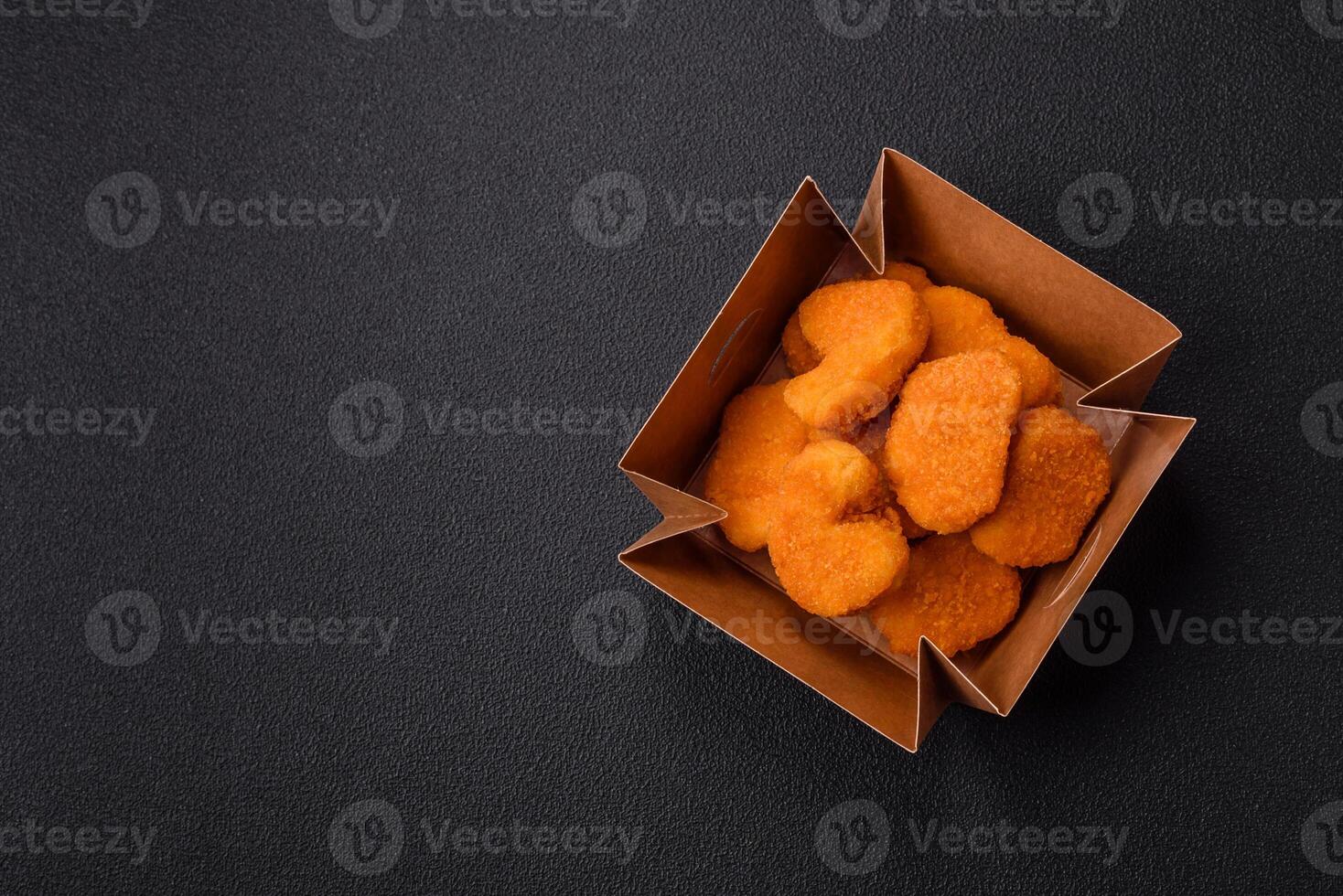 Delicious fresh crispy chicken nuggets on a dark concrete background photo
