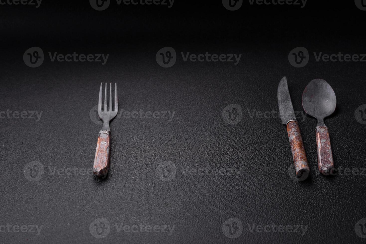 Cutlery fork, knife and spoon on a dark textured concrete background photo