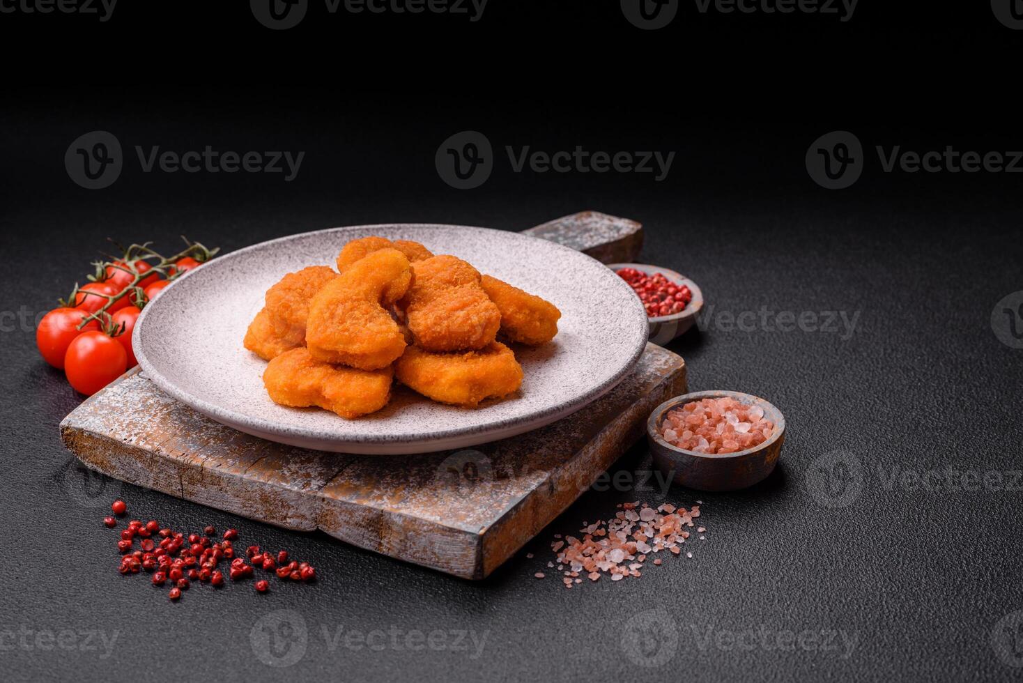 Delicious fresh crispy chicken nuggets on a dark concrete background photo