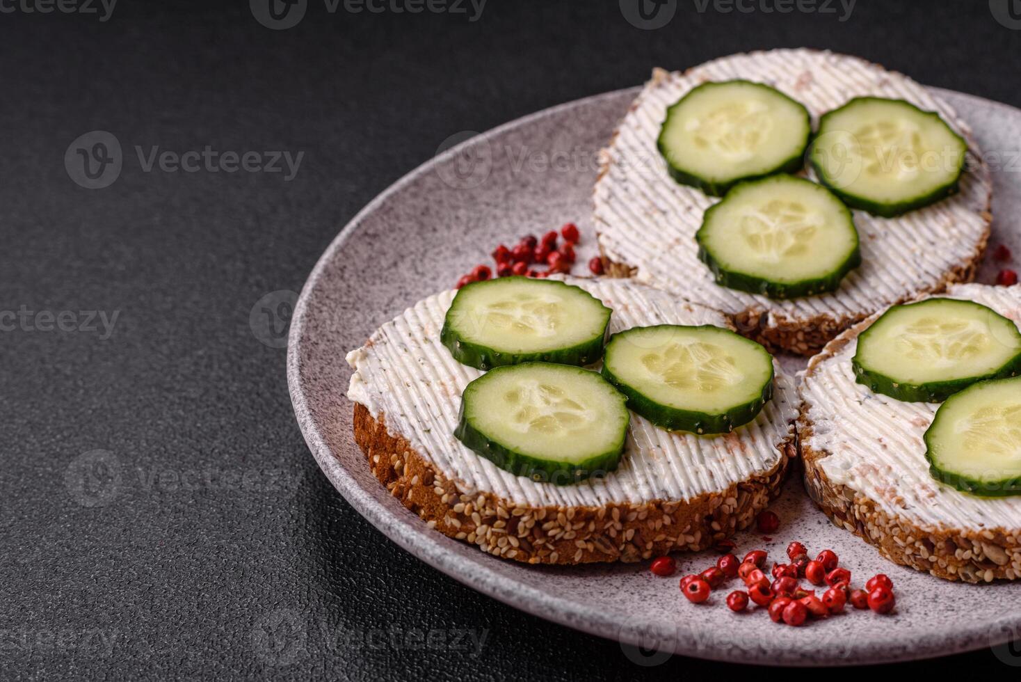 Delicious vegetarian sandwich with grilled toast, cream cheese, cucumbers and seeds photo