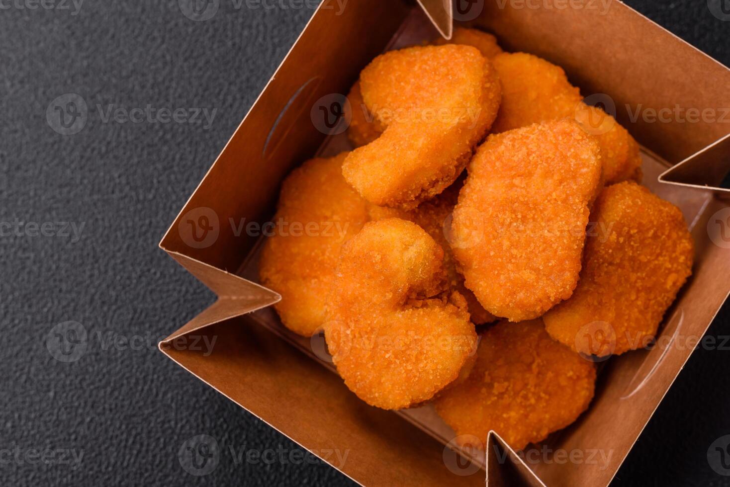 Delicious fresh crispy chicken nuggets on a dark concrete background photo