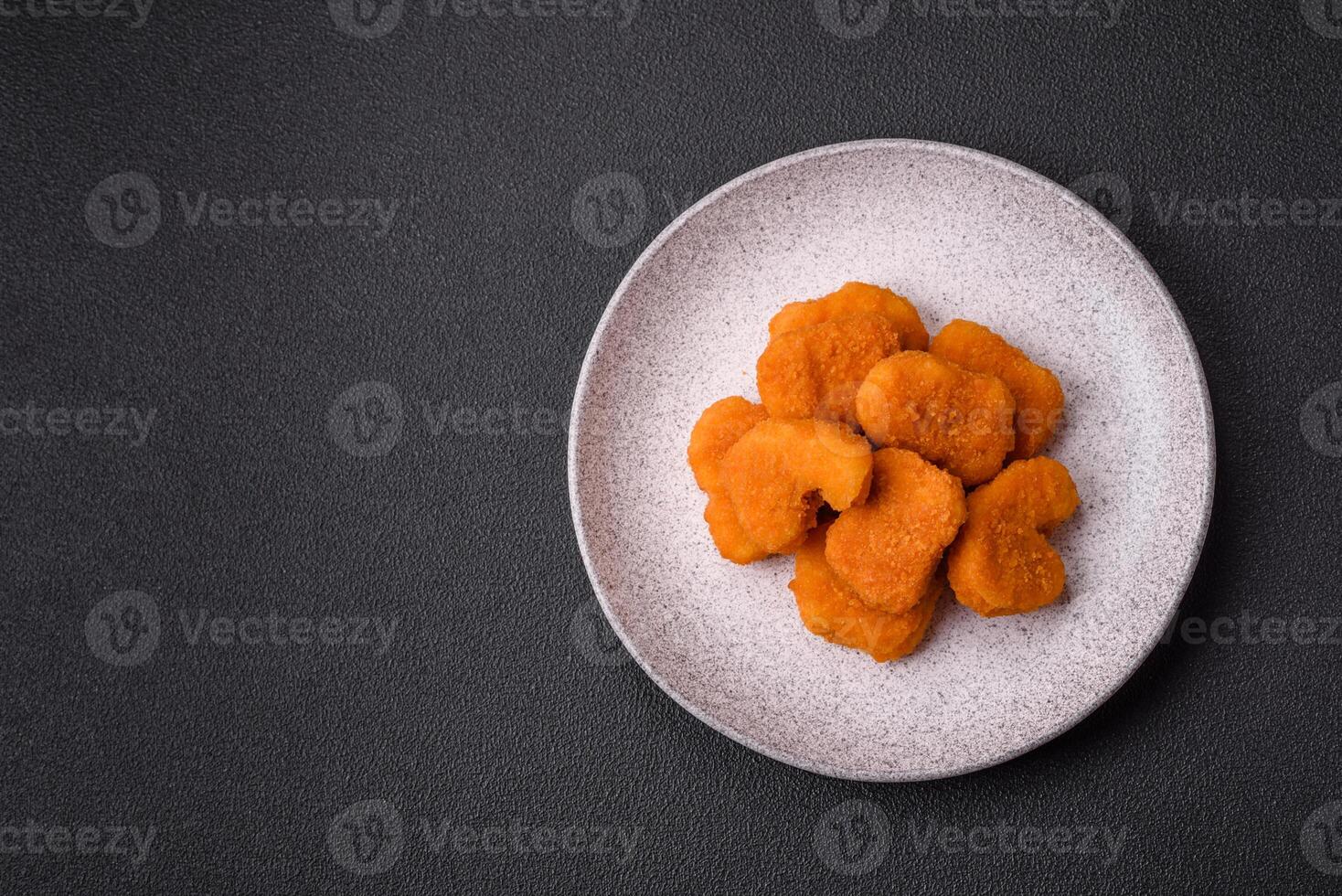 Delicious fresh crispy chicken nuggets on a dark concrete background photo