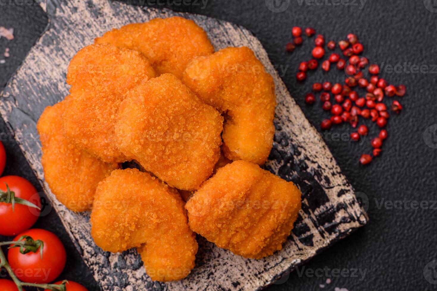 Delicious fresh crispy chicken nuggets on a dark concrete background photo