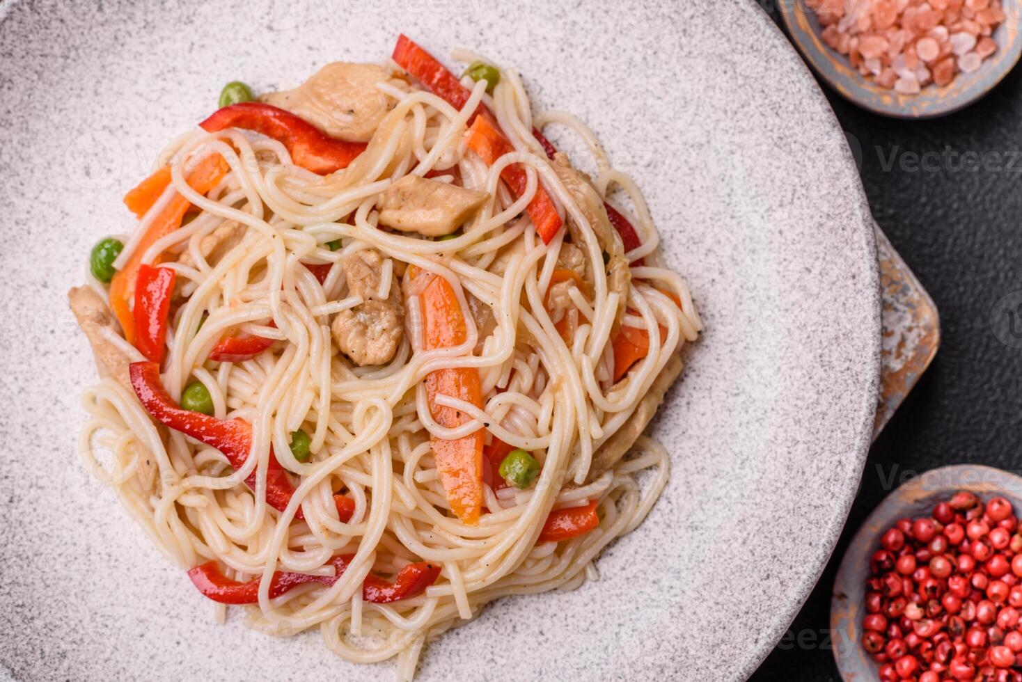Delicious rice noodles or udon with chicken, carrots, pepper, salt, spices and herbs photo