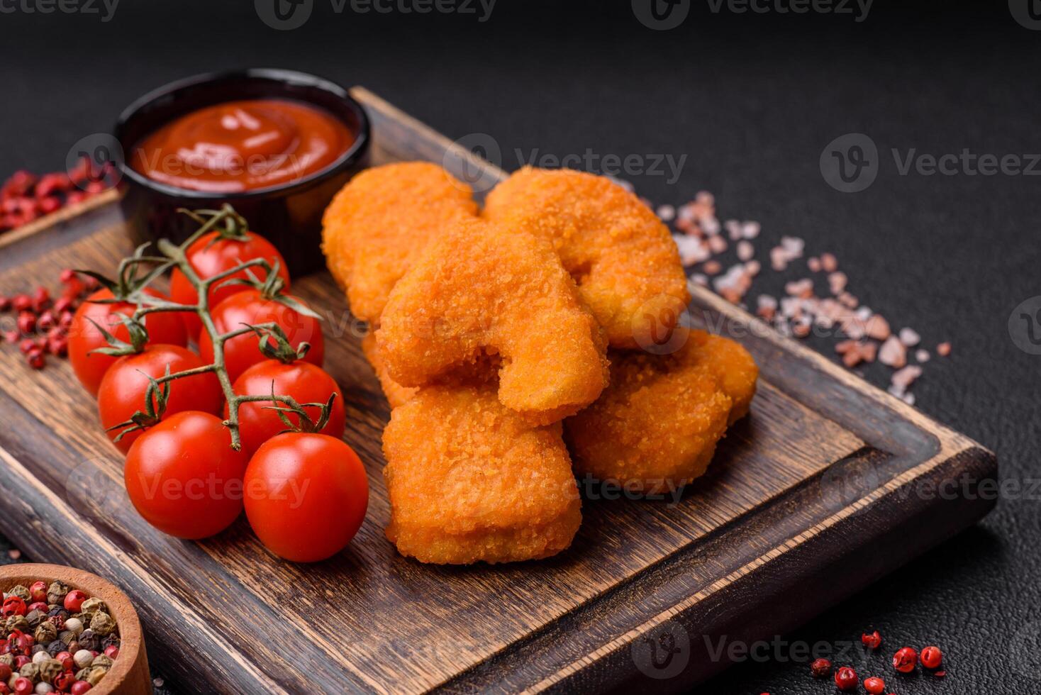Delicious fresh crispy chicken nuggets on a dark concrete background photo