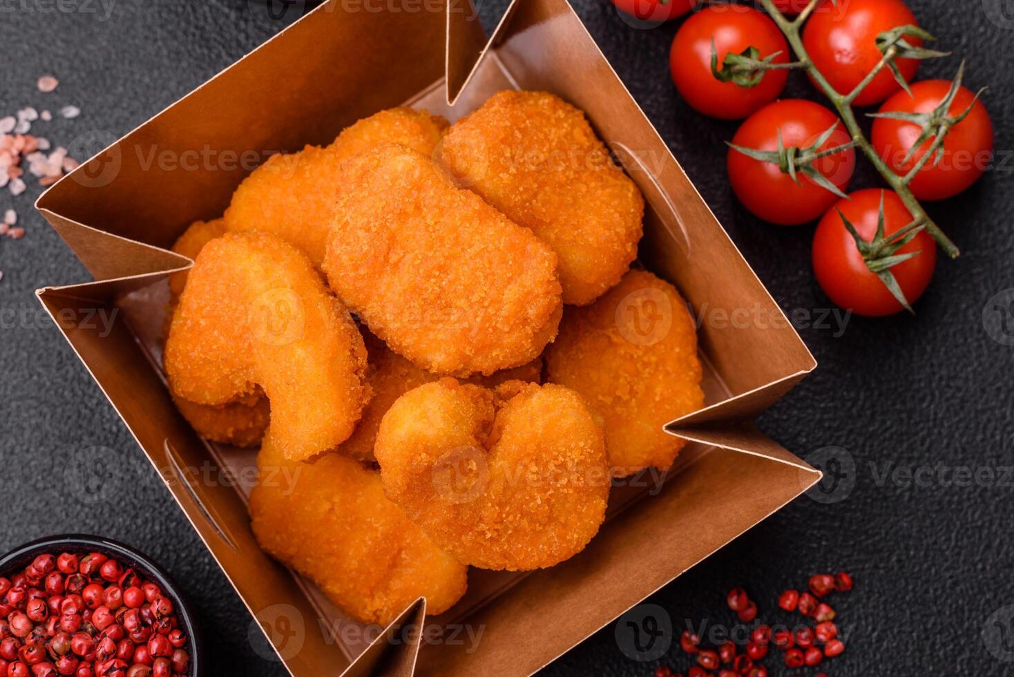 Delicious fresh crispy chicken nuggets on a dark concrete background photo