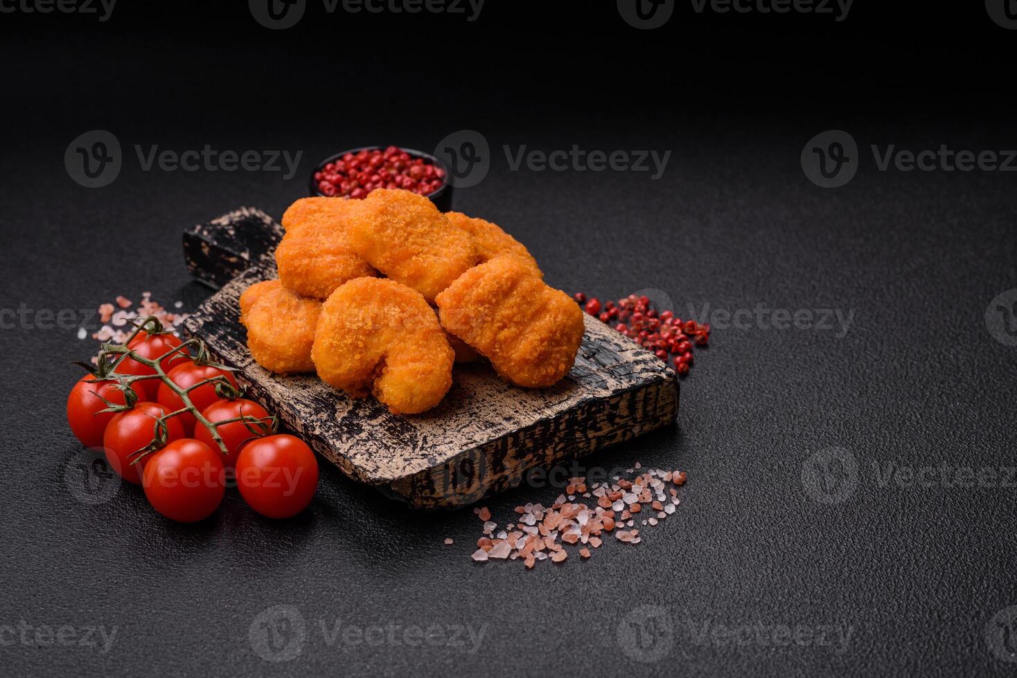 Delicious fresh crispy chicken nuggets on a dark concrete background photo