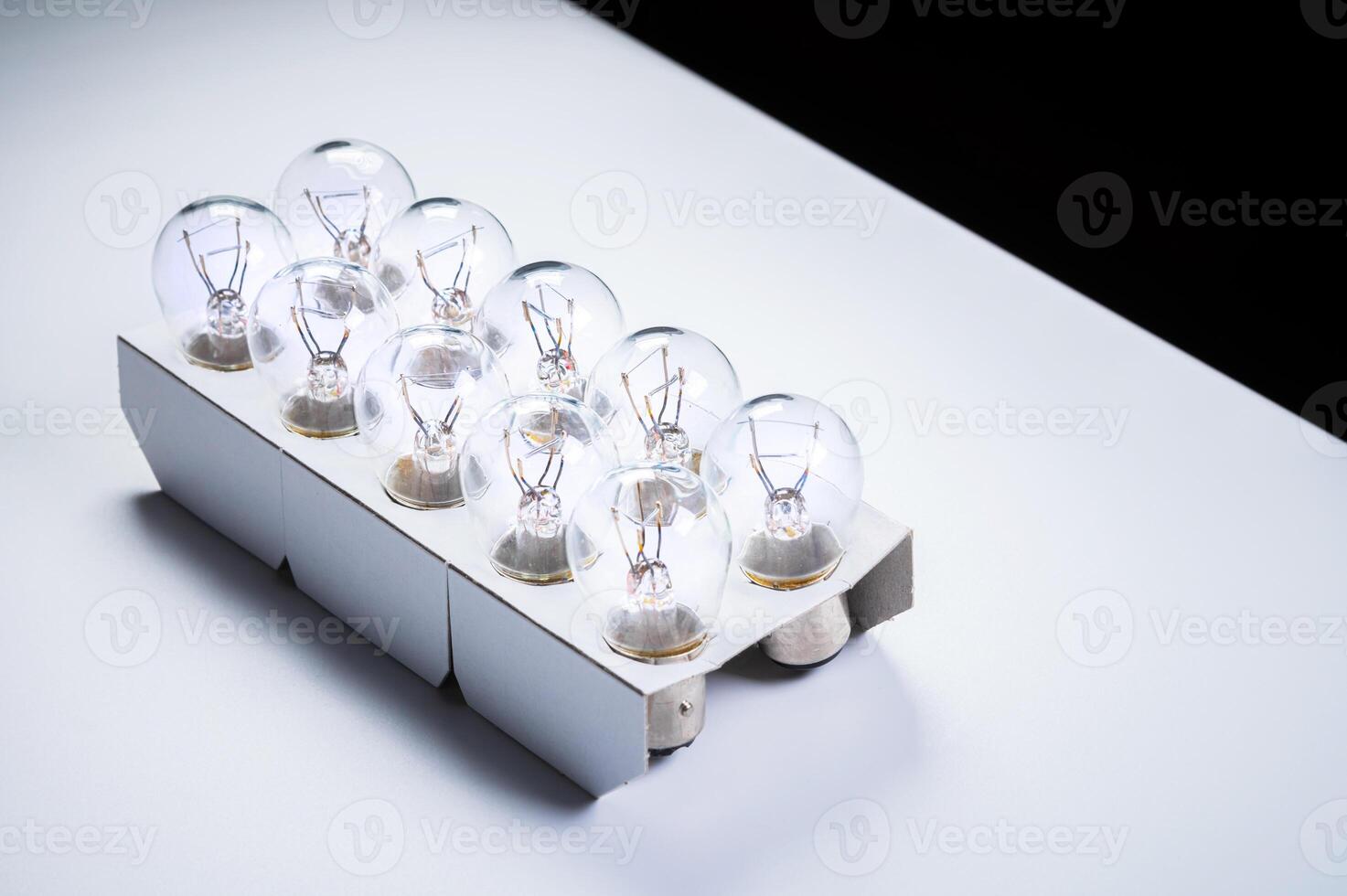 New incandescent car lamps for car sizes in paper-packed lot on a grey gradient background photo