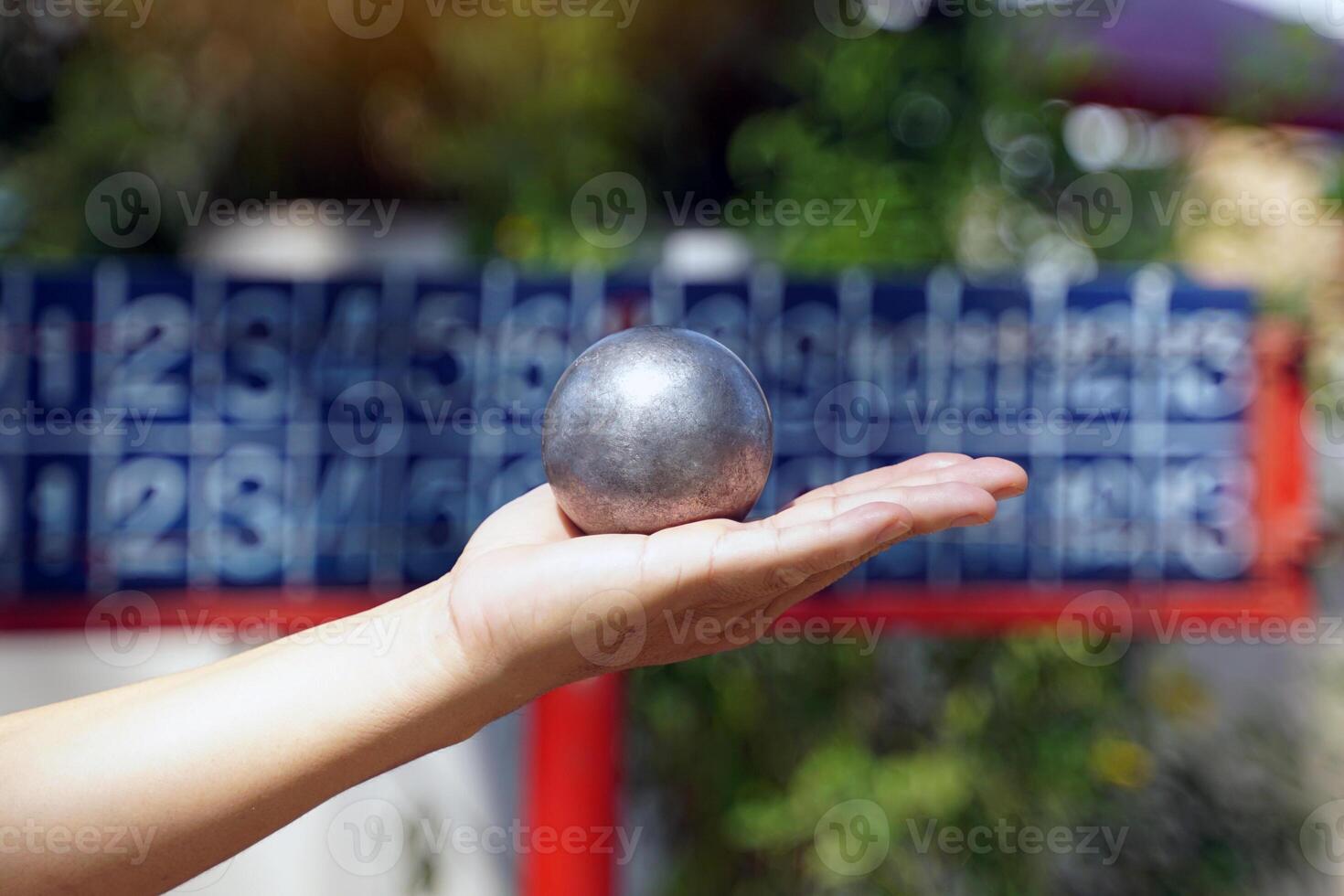 Players hold a petanque ball in their hands and prepare to throw it in order to place the petanque ball as close to the target ball as possible. photo