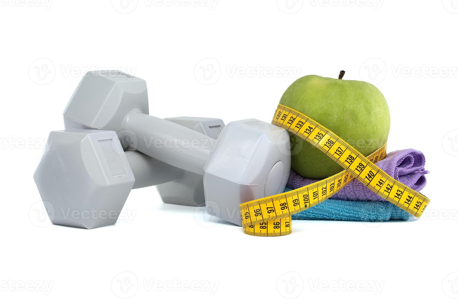 Two gray dumbbells and green apple with a tape measure photo