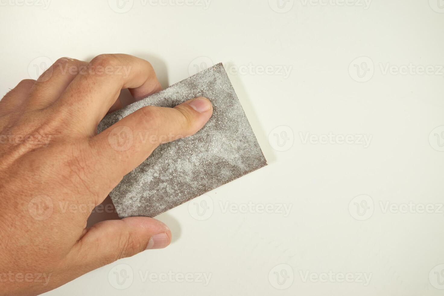 Hand sanding the wall with a sanding sponge photo