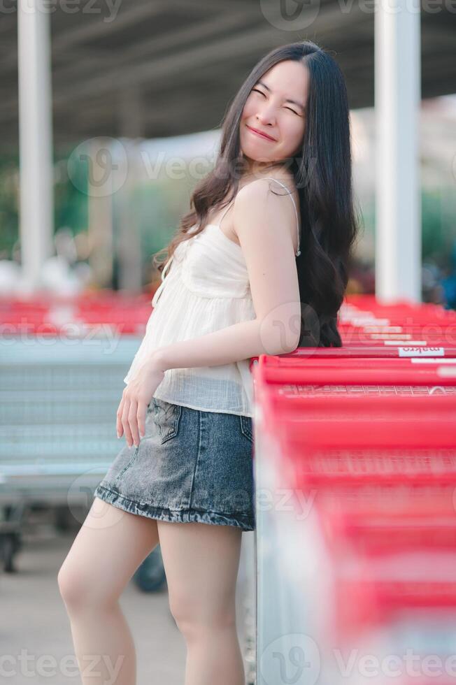 Beautiful Asian woman poses in fashion style, white shirt, jeans skirt. photo