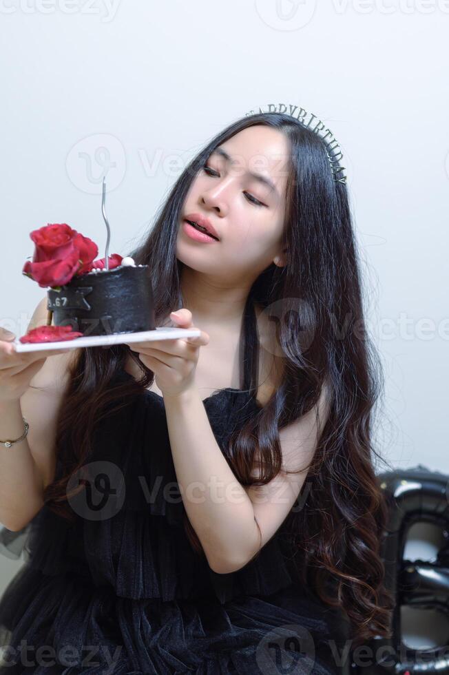 hermosa mujer vistiendo un negro vestir y chocolate pastel en el concepto de cumpleaños foto