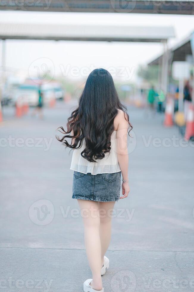 Beautiful Asian woman poses in fashion style, white shirt, jeans skirt. photo