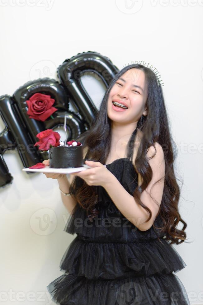 Beautiful woman wearing a black dress and chocolate cake in the concept of birthday photo