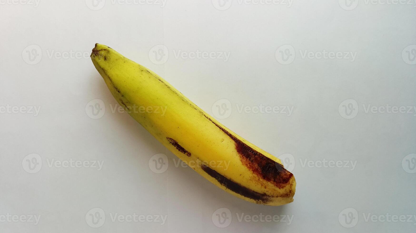 yellow banana with brownish black spots on a white background photo