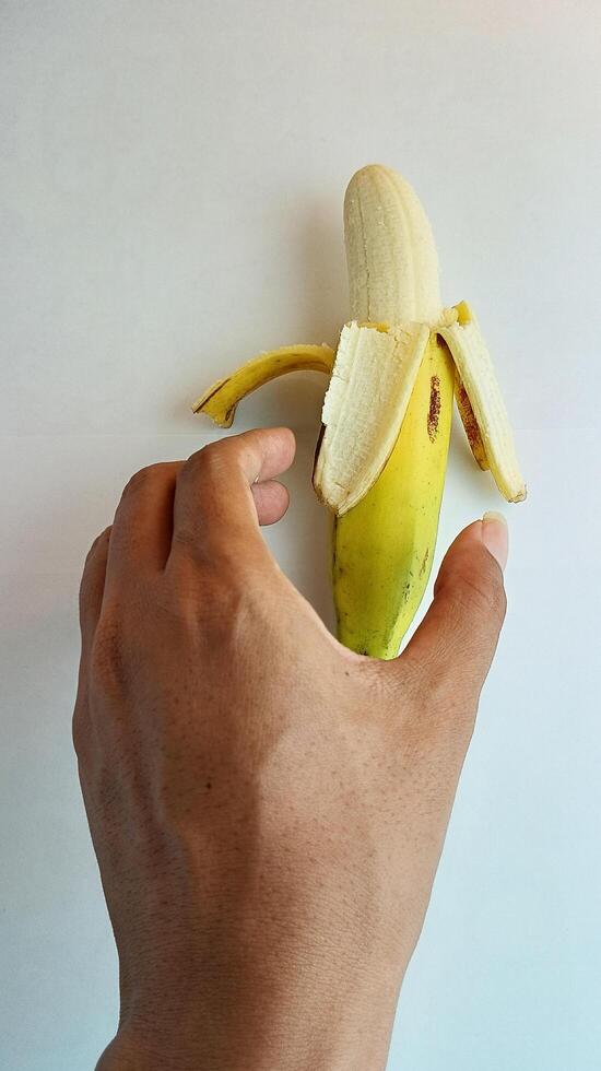 hand holding a yellow banana on a white background photo