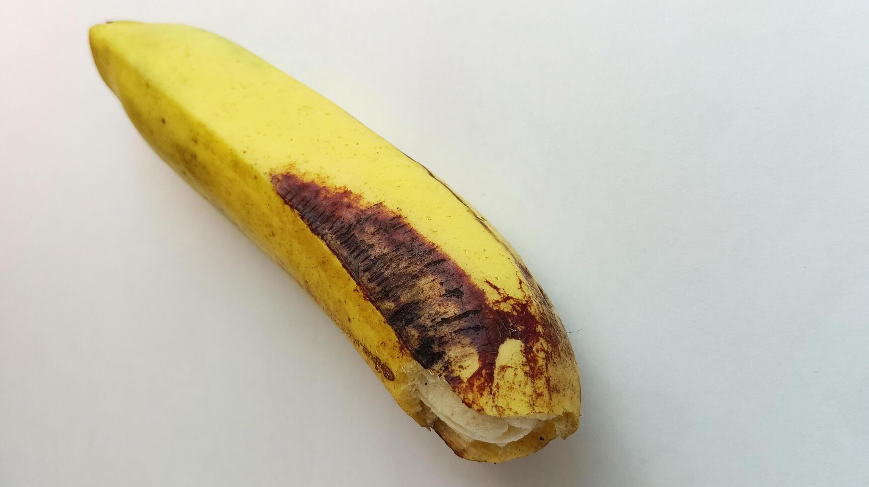 yellow banana with brownish black spots on a white background photo
