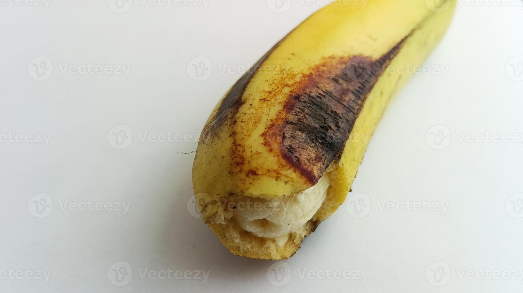 yellow banana with brownish black spots on a white background photo